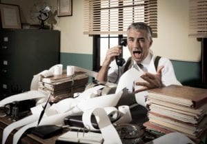 Angry vintage businessman shouting out loud at phone surrounded by adding machine tape.