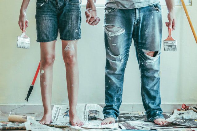 Two people holding hands and paint brushes
