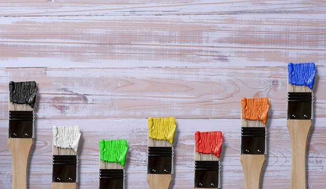 Alt-tag: A wooden wall and paintbrushes dipped in different colors, symbolizing a reason to build an online portfolio for your business in the painting industry