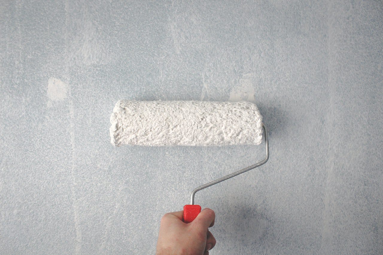 A hand holding a white paint roller