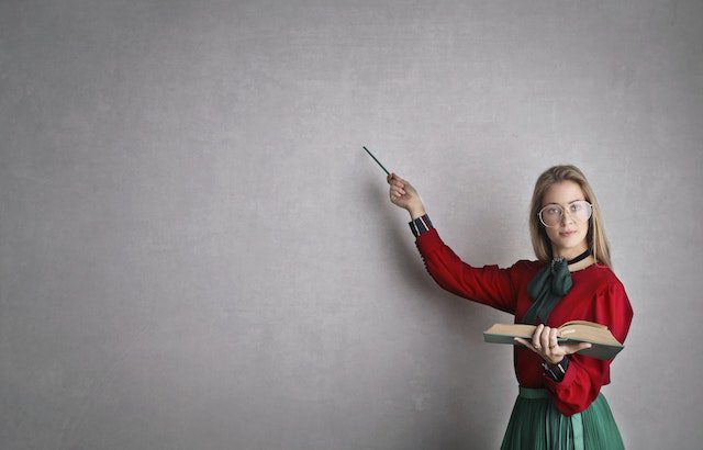 a woman pointing to a grey wall.