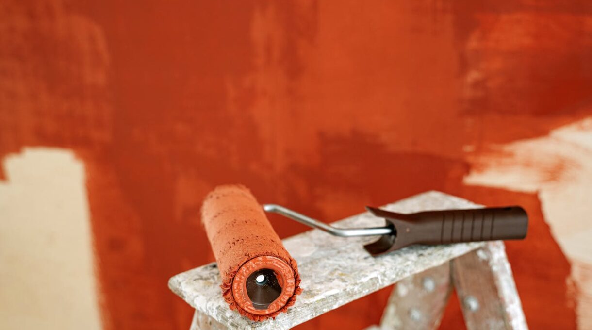 Paint roller with brown paint on a ladder